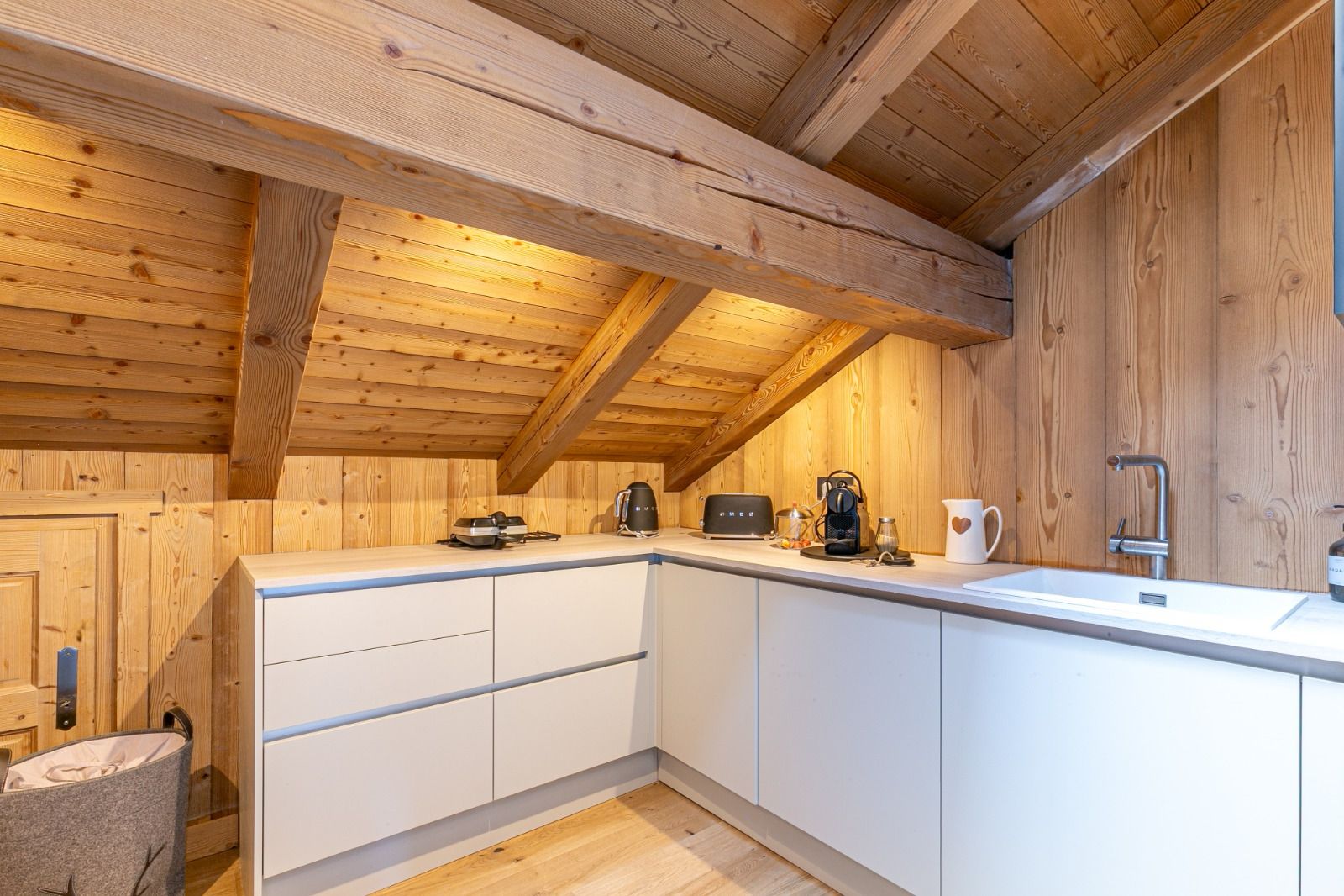 arrière cuisine, chalet, montagne, rangement, décoration, optimiser, optimisation, création de rangement, beau, bois, clair La configuration de l'appartement présentait quelques défis, notamment une cuisine de taille modeste et un conduit de cheminée mal positionné. Pour optimiser l'espace et répondre aux besoins d'un bien pouvant accueillir jusqu'à 14 personnes, nous avons imaginé une arrière-cuisine ingénieuse. Discrètement intégrée, elle offre un volume de rangement conséquent, permettant de préserver l'esthétique et la fluidité des pièces de vie principales.